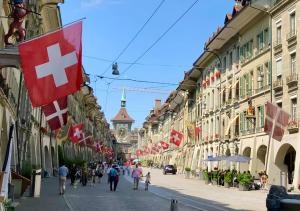 a street with flags and people walking down the street at Old Town Apartments - Self Check-In in Bern