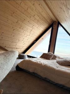 a bed in a room with a large window at LuMar Lodge Tohăniță Zarnesti in Zărneşti