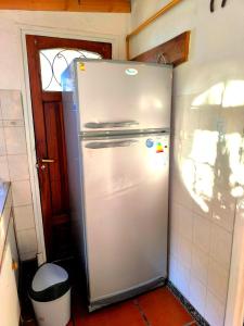 a refrigerator in a kitchen with a trash can at Hostel Küyen Mapu in Comodoro Rivadavia