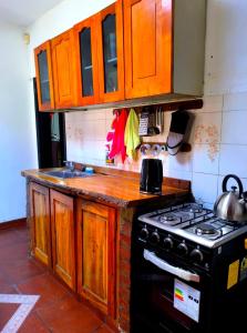 a kitchen with wooden cabinets and a stove top oven at Hostel Küyen Mapu in Comodoro Rivadavia