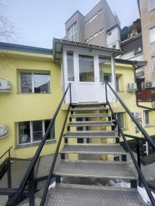 a staircase leading to a yellow building with a white door at Апартамент ФЕРДИНАНД in Ruse