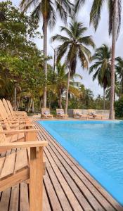 a swimming pool with lounge chairs and palm trees at Playa Mulata in Moñitos