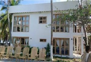 a white house with chairs in front of it at Playa Mulata in Moñitos +4 photos