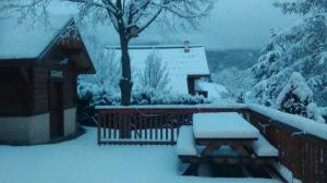 ギレストルにあるLa Carlineの雪に覆われた家の前のテーブルとベンチ