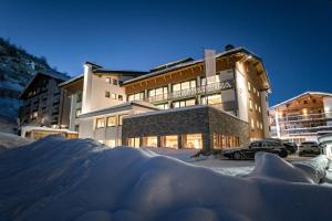 a building with a pile of snow in front of it at Hotel Albona Nova in Zürs am Arlberg