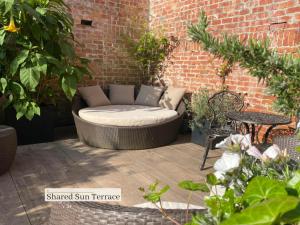 a wicker couch sitting on a patio with plants at B&B Royal Swans - Adults-Only Boutique Stay in Bruges in Bruges