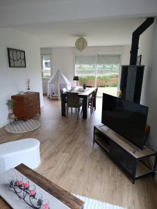 a living room with a tv and a dining room table at Maison bretonne 119 m2 - jardin clos - 30 min Côte Émeraude in Plénée-Jugon