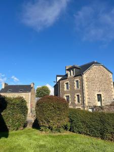 a large brick building with a hedge in front of it at Maison bretonne 119 m2 - jardin clos - 30 min Côte Émeraude in Plénée-Jugon