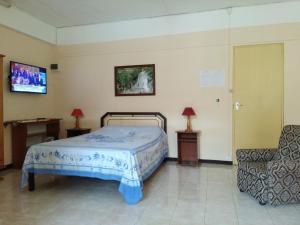 a bedroom with a bed and a chair and a television at Studio without kitchen at Alpha Villa in Flic-en-Flac