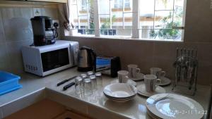 a kitchen counter with a microwave and some plates and cups at Studio without kitchen at Alpha Villa in Flic-en-Flac