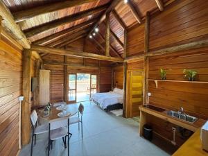 a bedroom in a wooden cabin with a bed and a sink at refugio in Aguas Mornas