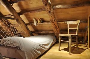 a bed and a chair in a room with wooden walls at Rustico La Stalla a Pianezza in Menzonio