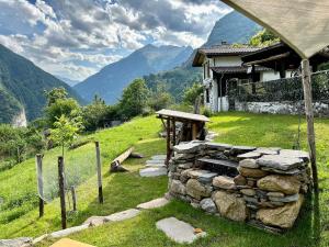 a stone wall next to a house in a field at Rustico La Stalla a Pianezza in Menzonio