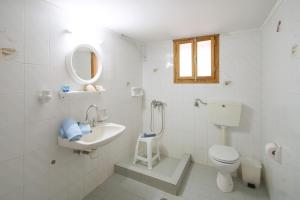 a white bathroom with a toilet and a sink at Angela studios in Troulos