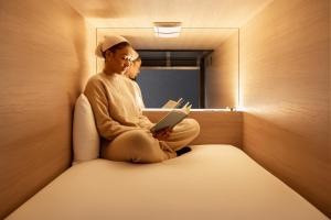 two people sitting in a room with a laptop at Zedwell Capsule Hotel Piccadilly Circus in London