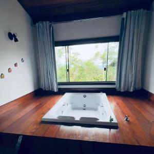 a bath tub in a room with a large window at Chalés Lavras de Minas - Canadá in Lavras Novas