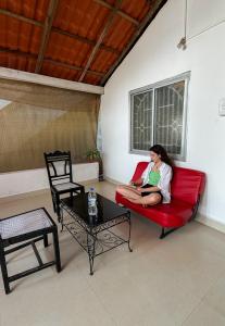 a woman sitting on a red couch in a living room at This is it Stays - Beach View Rooms & Huts in Arambol +58 photos