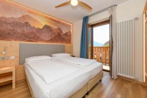 a bedroom with a large bed and a large window at Hotel Denny in Pinzolo