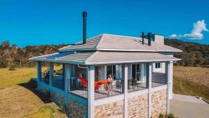 a house with a wrap around porch with a woman sitting on the balcony at Casa Paraíso do Sol - Rancho Queimado - SC in Rancho Queimado