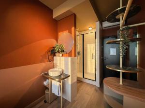 a bathroom with orange walls and two tables in a room at De Pijp Hotel in Amsterdam