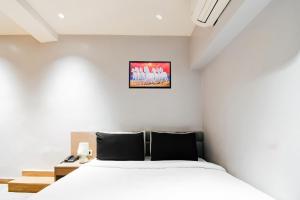 a white bedroom with a bed and a desk at Hotel O Sivalika Inn in Kolkata
