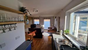 a kitchen with a sink and a living room at Sea Drift Self Catering in Dunan