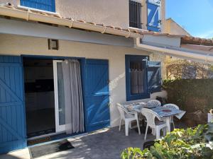 a patio with blue doors and a table and chairs at maison 100 m de la plage à pieds in Portiragnes