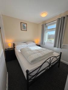 a bedroom with a bed with white sheets and a window at 116, Two bed Chalet on California Sands Holiday Park - Sleeps 5, pet friendly, includes FREE pool passes, Free Entry to Clubhouse - plus Electric, WiFi, bed linen and towels all included - only 300m from the beach! in Scratby +17 photos