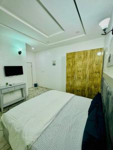 a bedroom with a white bed and a television at The Cape - Apartment in Bamgbose