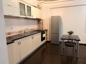a kitchen with white cabinets and a table and a refrigerator at Bella Home Residence2 in Roşu +2 photos