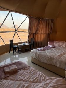 a room with two beds and a large window at The Martian Bubbles - Wadi Rum in Wadi Rum