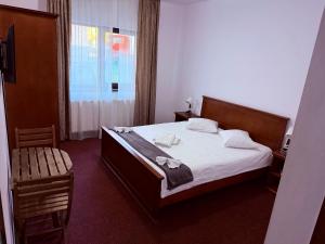 a bedroom with a bed and a chair and a window at GRAND Caciulata in Caciulata