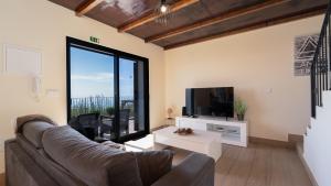 a living room with a couch and a tv at Casa da Felicidade by LovelyStay in Prazeres