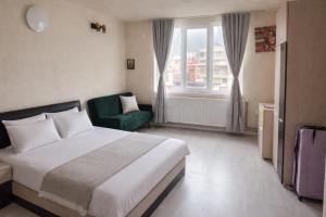 a hotel room with a bed and a green chair at Апартамент Зора in Chepelare