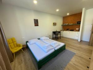 a bedroom with a bed and a yellow chair at Alipoint Apartments in Spišské Podhradie