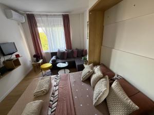 a bedroom with a large bed and a living room at Moderan Studio na Trgu Republike - Centar in Podgorica +3 photos