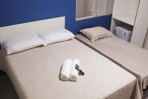 a bed with two white slippers and a remote control on it at Pousada Porto Maresias in Cabo Frio +43 photos