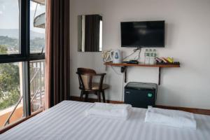 a bedroom with a bed and a balcony with a television at Riverside Houayxay Hotel in Ban Houayxay
