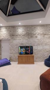 a living room with a tv on a stone wall at Nethercoombe House in Portland