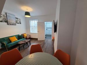 a living room with a green couch and a table at LEB Homes UK, 3 Bedroom House - 2 mins walk to station in Crawley