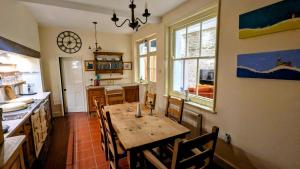 a kitchen with a table and chairs and a clock on the wall at Nethercoombe House in Portland