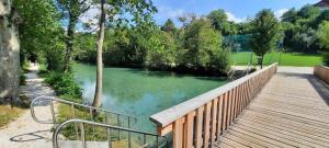 a wooden walkway leading to a river with green water at MühlengasseONE in Lenzing
