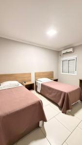 a room with two beds and a window at Imbau Palace Hotel in Imbau