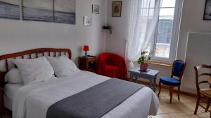 a bedroom with a bed and two chairs and a window at Studio Neptune in Arromanches-les-Bains