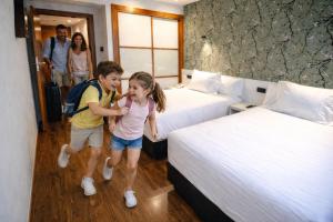 a boy and girl in a hotel room with two beds at Hotel Apartamentos San Fermín Pamplona in Pamplona