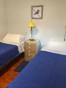 a bedroom with two beds and a lamp on a dresser at TINY HOUSE EL ROBLE in Puerto Varas