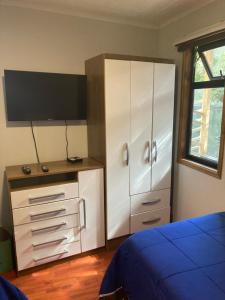 a bedroom with a white cabinet and a tv at TINY HOUSE EL ROBLE in Puerto Varas