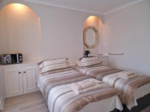two beds in a white room with a mirror at Osterley Room in Isleworth