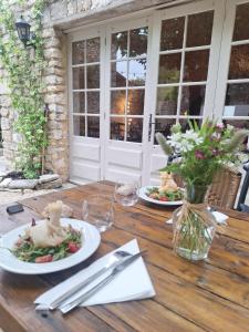a wooden table with two plates of food on it at Hôtel restaurant Clos des Sullys in Montclus