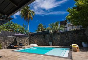a swimming pool in front of a stone wall with a house at Seascape Villa in Pointe aux Biches